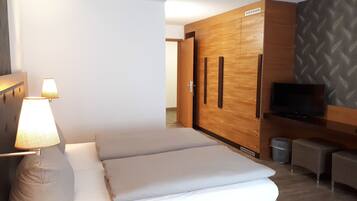 Ett hotellrum med en säng, en TV, en garderob och en lampa.