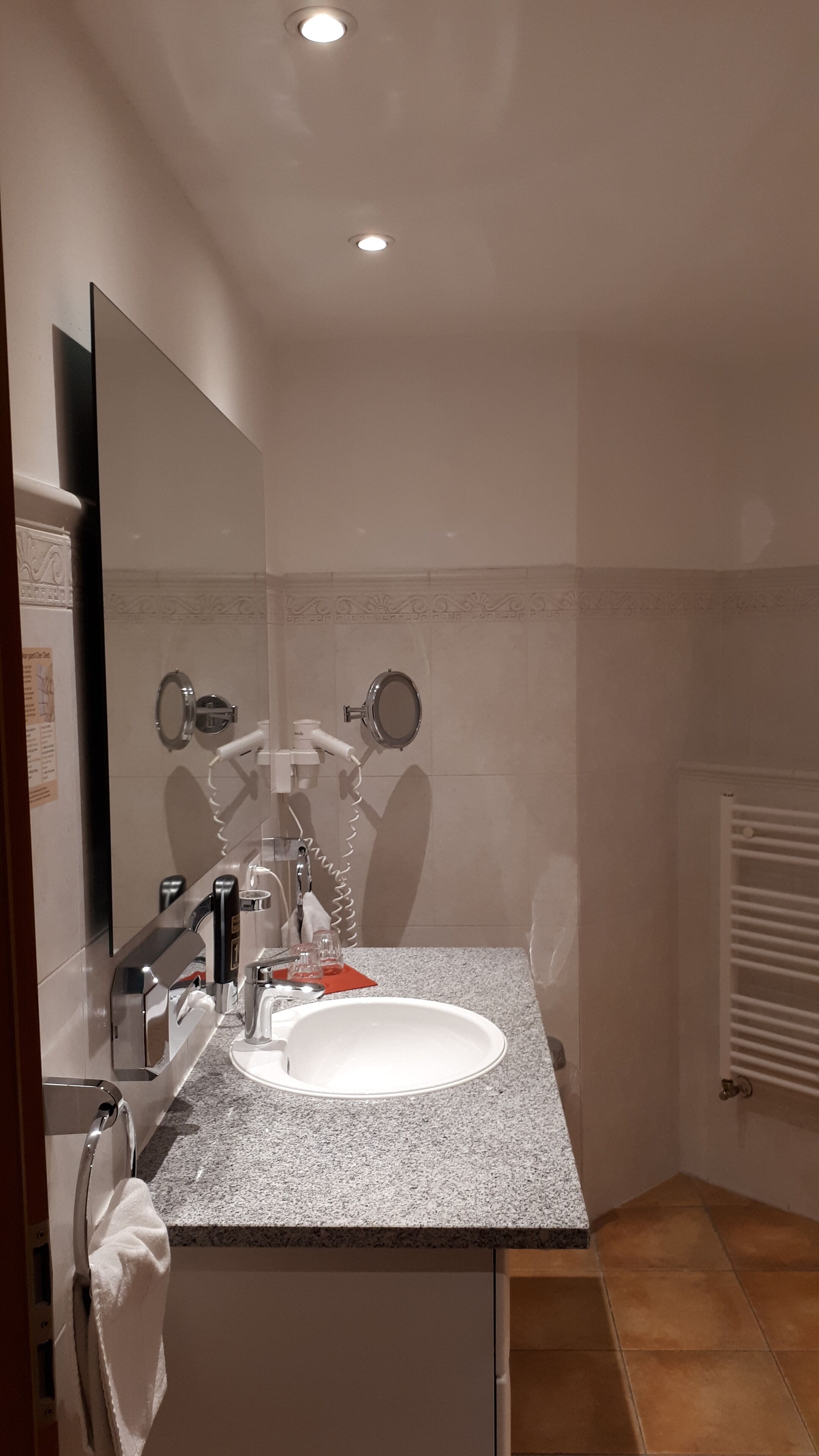 A bathroom with a white sink, a mirror, a towel rack, and a towel hanging on it.