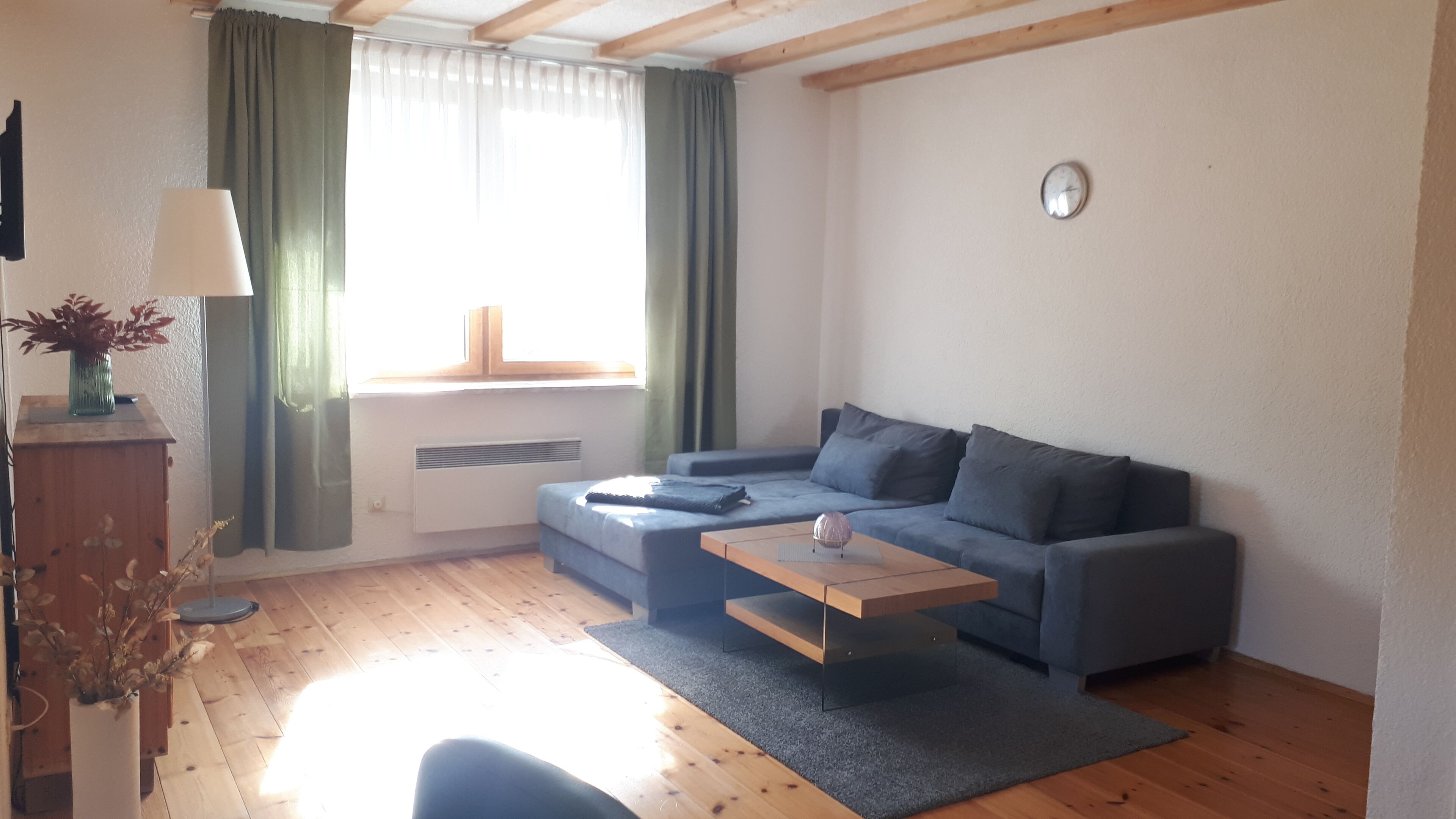 Ein modernes Wohnzimmer mit einer Couch, einem Holztisch und einer Heizung.