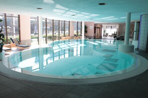 Una piscina techada, sillones reclinables de piscina