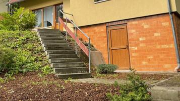 Ein zweistöckiges Haus mit Holzbalkon, Ziegelaußenwand und einer Treppe zum Eingang.