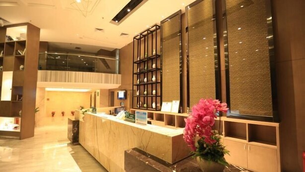 A hotel reception area with a marble floor, a reception desk, a TV, and a decorative plant. - Shanshui Trends Hotel Pingtan Branch (Fuzhou)