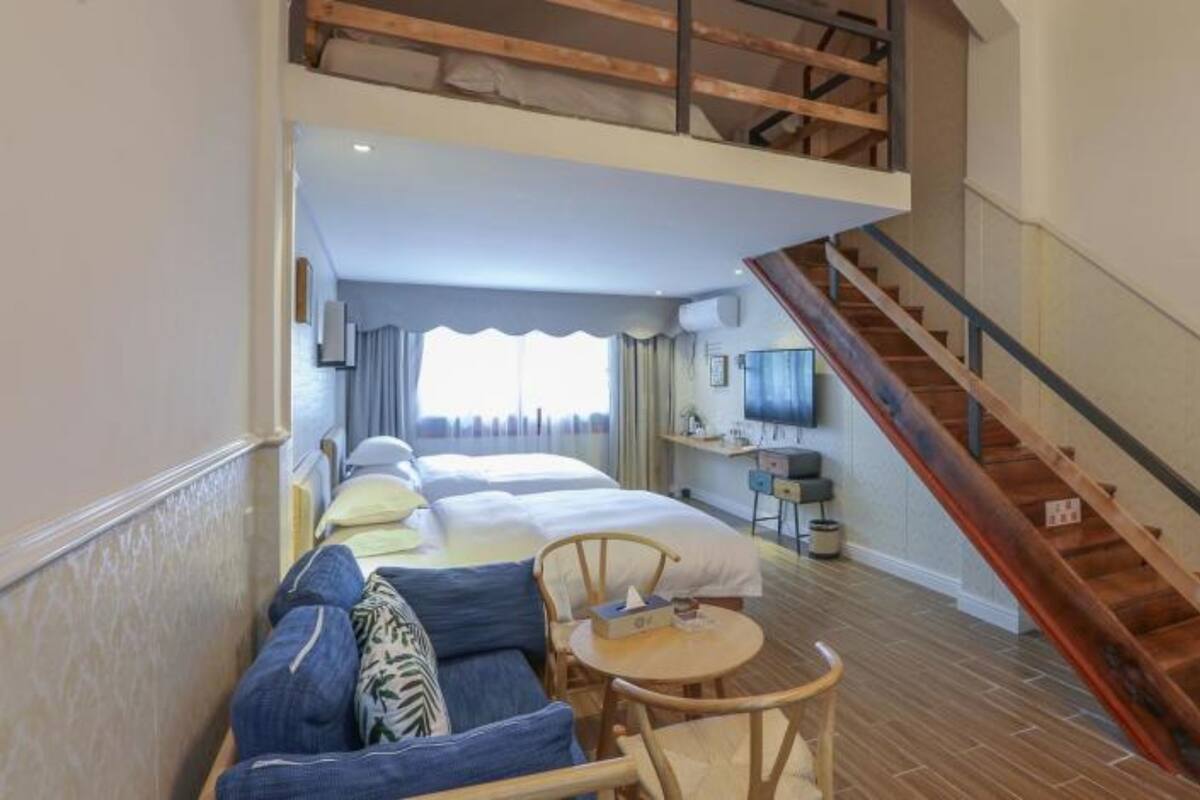 Una habitación de hotel con cama tipo loft, un sofá, una mesita y una escalera.