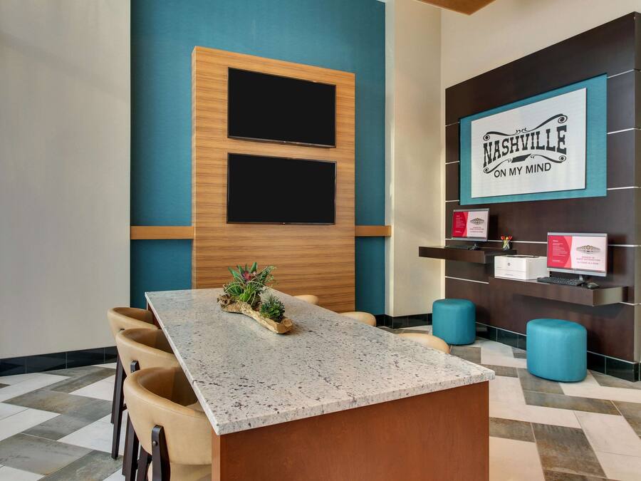 A modern reception area with a marble counter, two televisions mounted on a wooden panel, and a sign reading "Nashville on my mind".