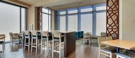 A modern hotel lobby with a bar area, seating, and large windows.
