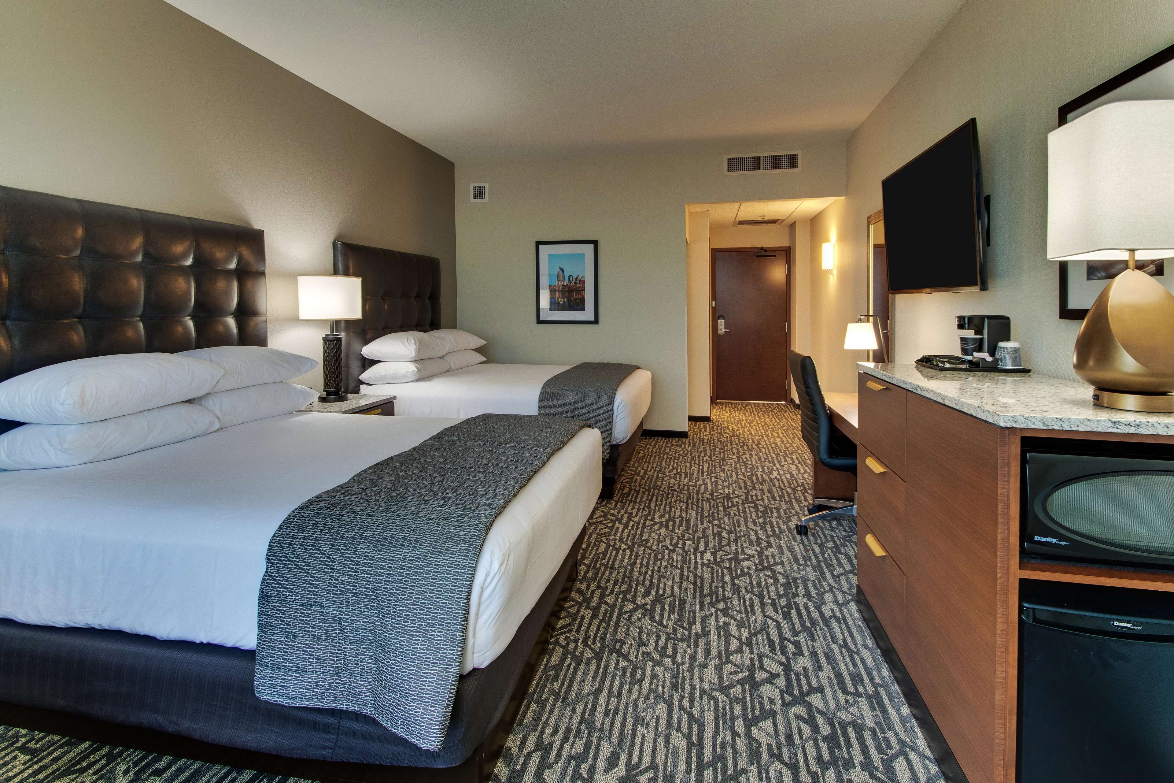 Une chambre d’hôtel avec deux lits, un bureau, une télévision et une salle de bain.