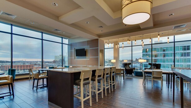 A modern bar area with a high ceiling, large windows, and a city view. - Drury Plaza Hotel Nashville Downtown (Nashville)