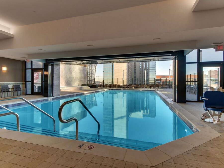 Una piscina interior con paredes de vidrio transparente, suelo de baldosas y un cartel que indica una profundidad de 1,2 metros.