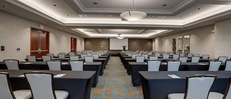 A conference room with rows of tables and chairs, a patterned carpet, and a modern ceiling design.