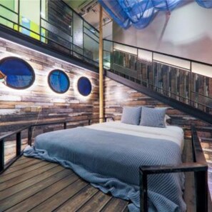 A bedroom with a wooden floor, a bed with a blue blanket, and a staircase with a railing. - Floral Hotel Chongqing Meila (Chongqing)