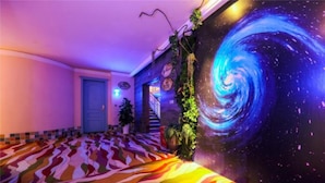 Un pasillo con una alfombra de diseño colorido, un mural grande que representa una galaxia y una escalera con plantas.