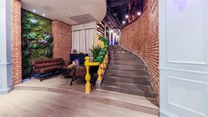 Un espacio interior acogedor con pared de ladrillo, una escalera y una zona de estar con sofá y mesa.