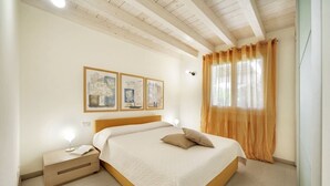 Une chambre à coucher avec un lit en bois, une table de chevet avec une lampe et trois œuvres d’art encadrées accrochées au mur.