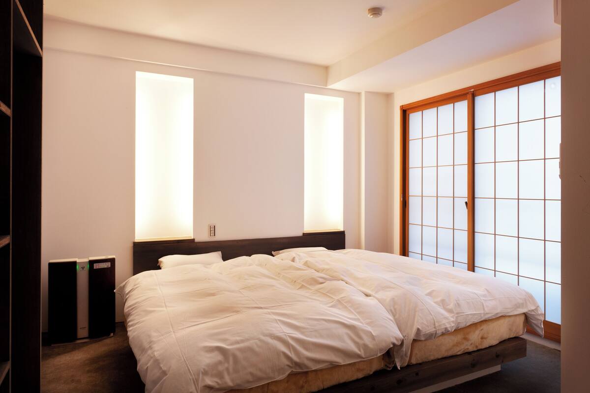 Een slaapkamer met een groot bed, een houten hoofdbord en een schuifdeur van papier.