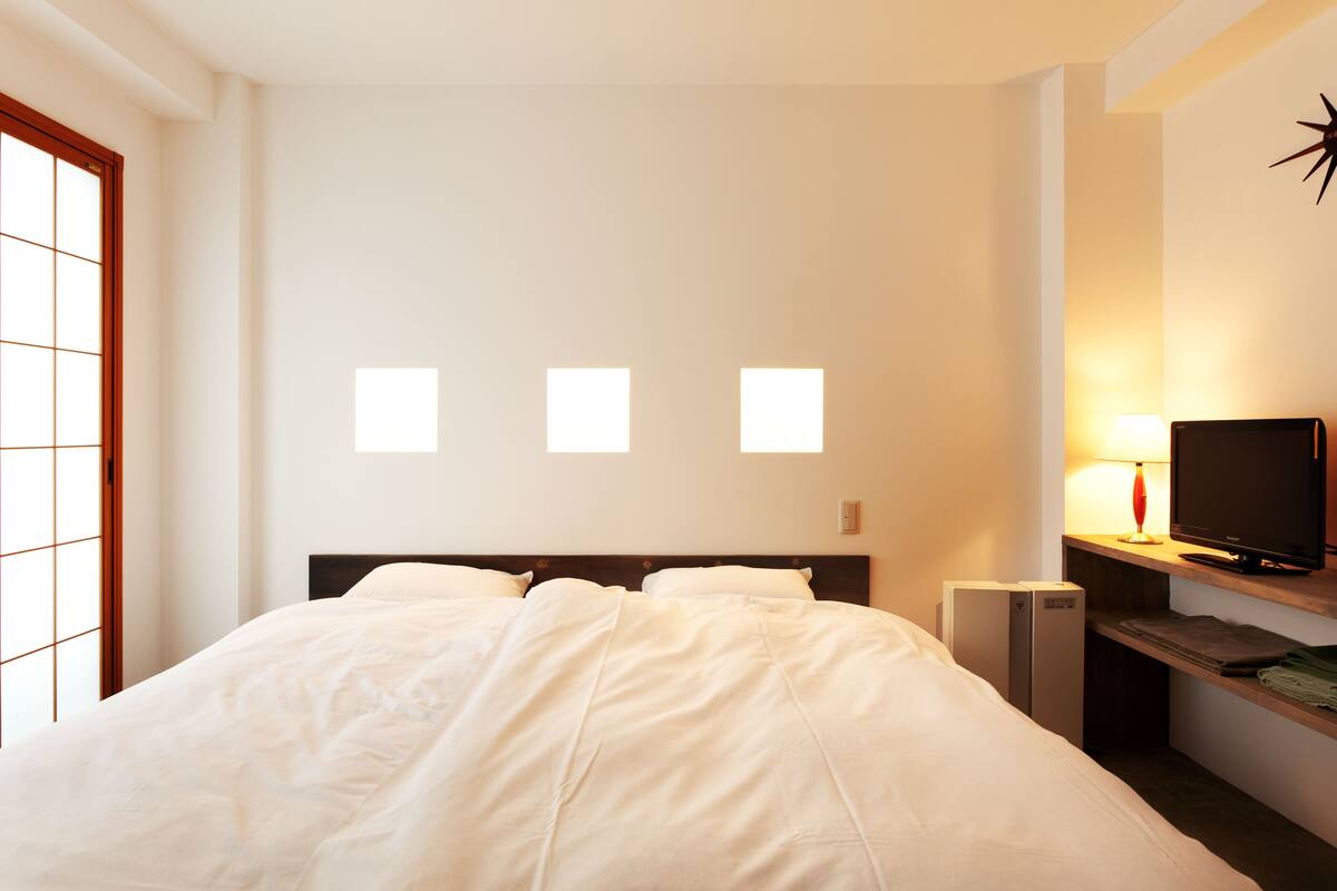 Een hotelkamer met een bed, een bureau met een computer, een televisie en een raam met uitzicht op het buiten.