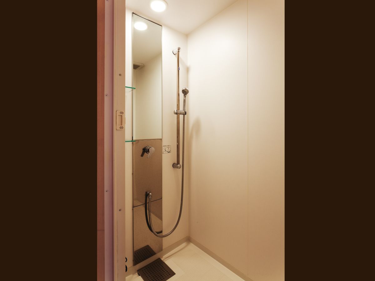 A small, modern bathroom with a shower, a mirror, and a door.