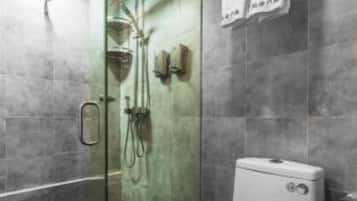 A modern bathroom with a glass-enclosed shower, a white toilet, and a towel rack with two towels.