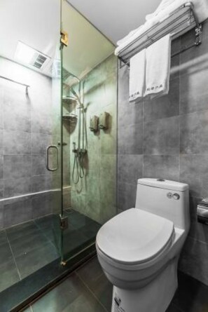 A modern bathroom with a glass-enclosed shower, a white toilet, and a towel rack with two towels. - Floral Hotel Langzhong Pangmen College (Nanchong)