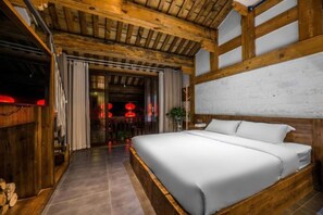 A bedroom with a large bed, wooden beams on the ceiling, and a white wall. - Floral Hotel Langzhong Pangmen College (Nanchong)