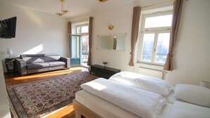 A bedroom with a large bed, a sofa, a mirror, and a television. - Hotel Vila Katrca (Ljubljana)