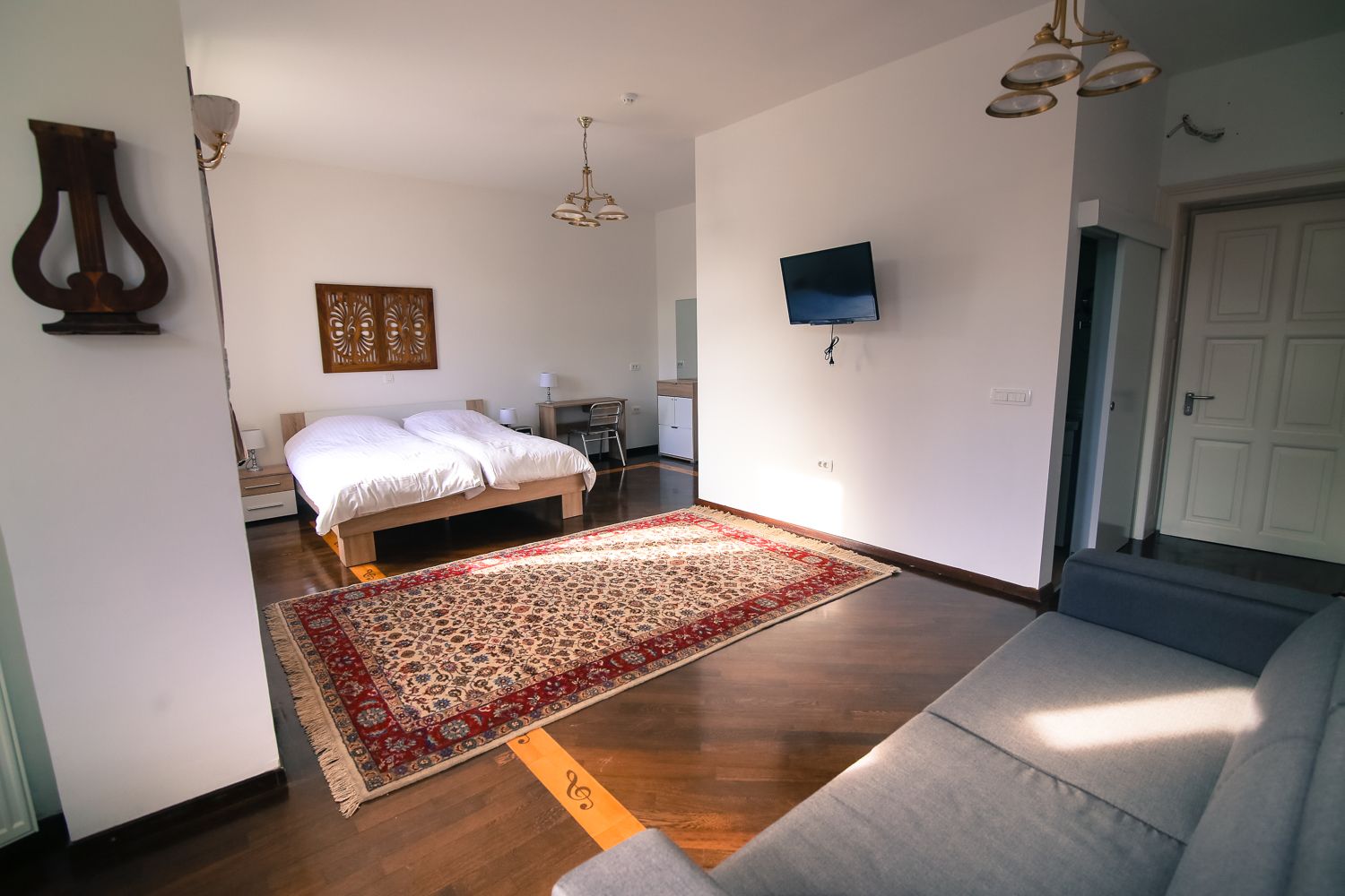 Ein Schlafzimmer mit einem großen Bett, einem an der Wand montierten Fernseher und einem Holzboden.