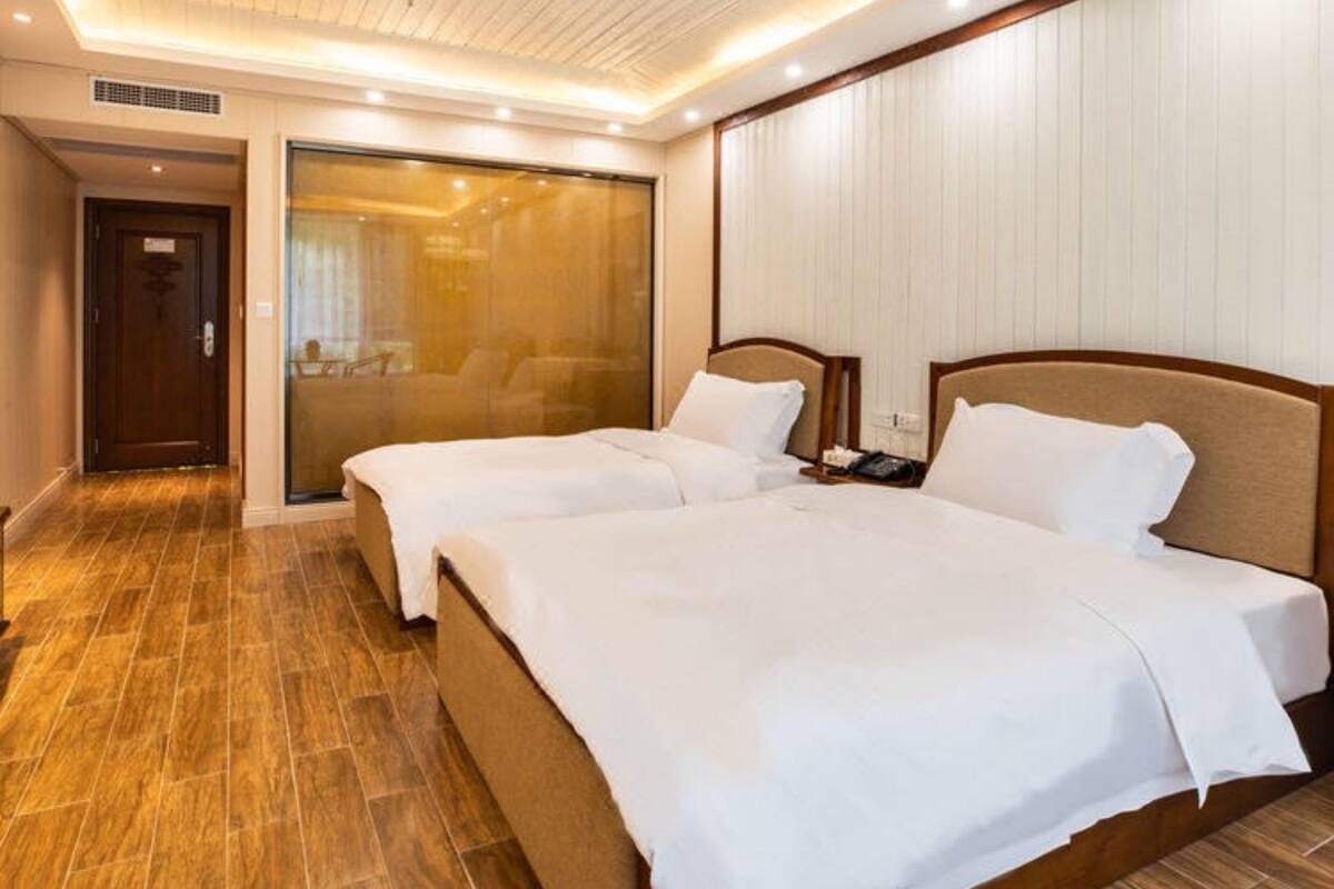 Habitación de hotel con dos camas, piso de madera, un amplio ventanal corredera e iluminación empotrada en el techo.