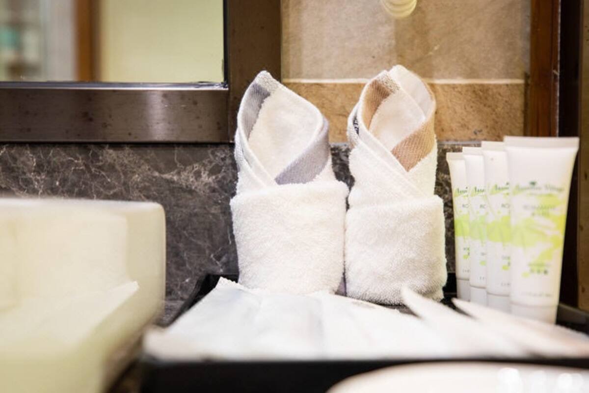 Una encimera de baño con artículos de aseo, incluyendo una toalla, un dispensador de jabón y una botella de loción.