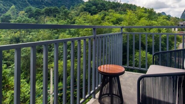 Un balcon offrant une vue sur de luxuriantes montagnes verdoyantes et un ciel dégagé.