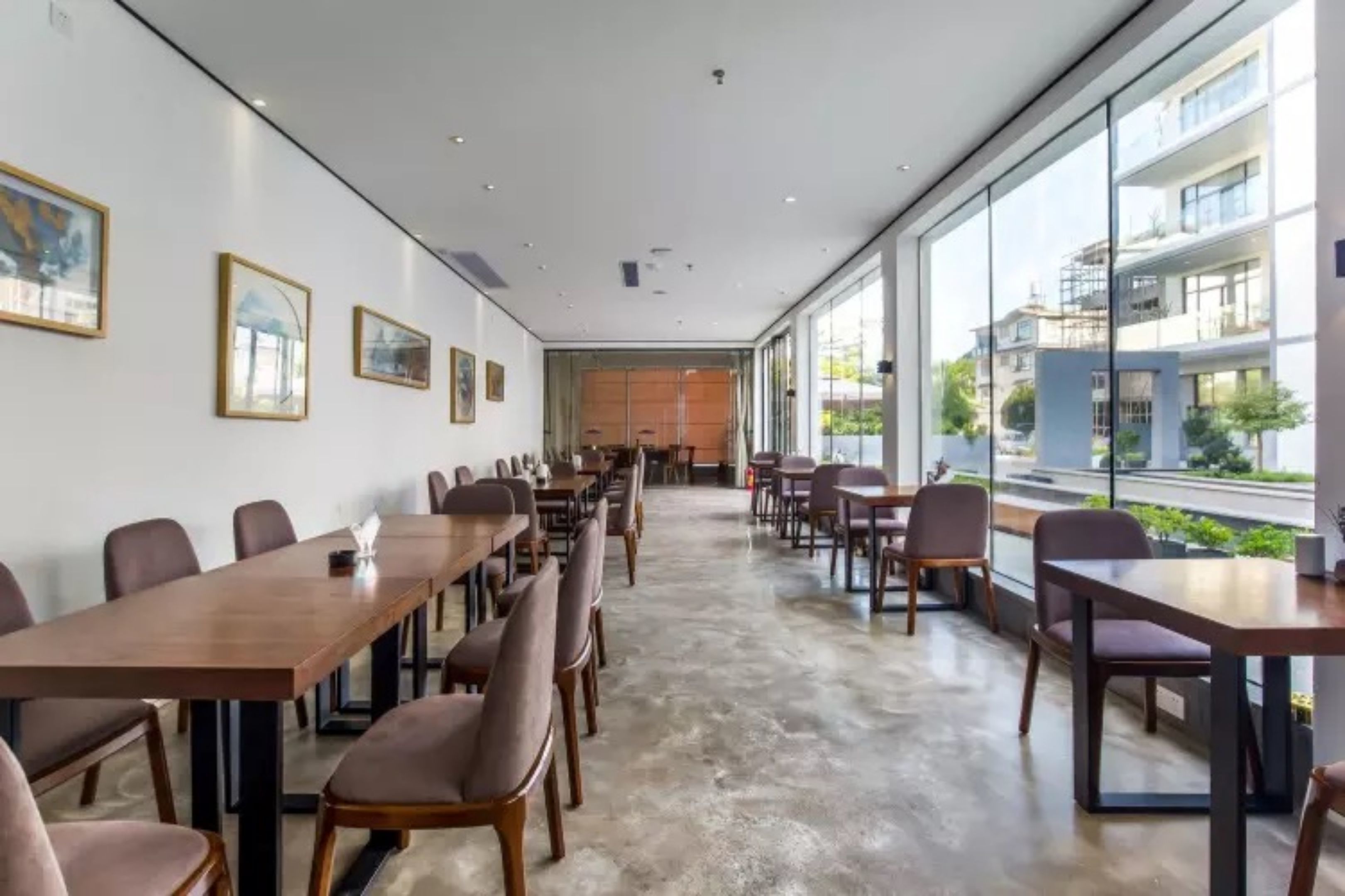 A modern conference room with long tables and chairs, large windows offering a view of the cityscape.