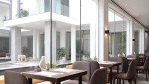 Un espace de restauration moderne avec des murs en verre, des tables et des chaises en bois.