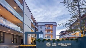 Un hôtel moderne doté d’une entrée imposante, d’une façade bien éclairée et d’une enseigne avec des caractères chinois.