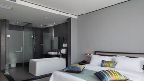Une chambre d’hôtel moderne dotée d’un grand lit, d’une salle de bain séparée et d’une douche à l’italienne.