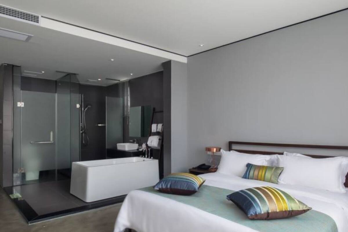 A modern hotel room with a large bed, a separate bathroom, and a glass-enclosed shower area.