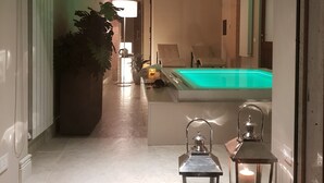 Un interior moderno con una piscina, una planta grande en maceta y dos lámparas con diseño de farol.