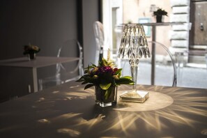 Una mesa con un jarrón de vidrio transparente con flores, una lámpara de vidrio transparente y un cofre de vidrio transparente.