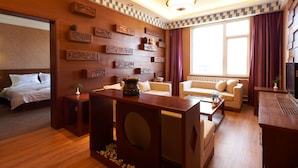 A hotel room with a bed, a sofa, a coffee table, and a TV. - Floral Hotel Shangri-la Budange (Deqin)
