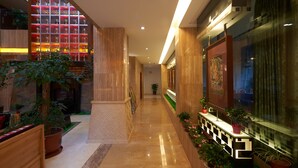 A modern hotel corridor with a glass wall displaying trophies, a wooden bench, potted plants, and a framed artwork on the wall. - Floral Hotel Shangri-la Budange (Deqin)