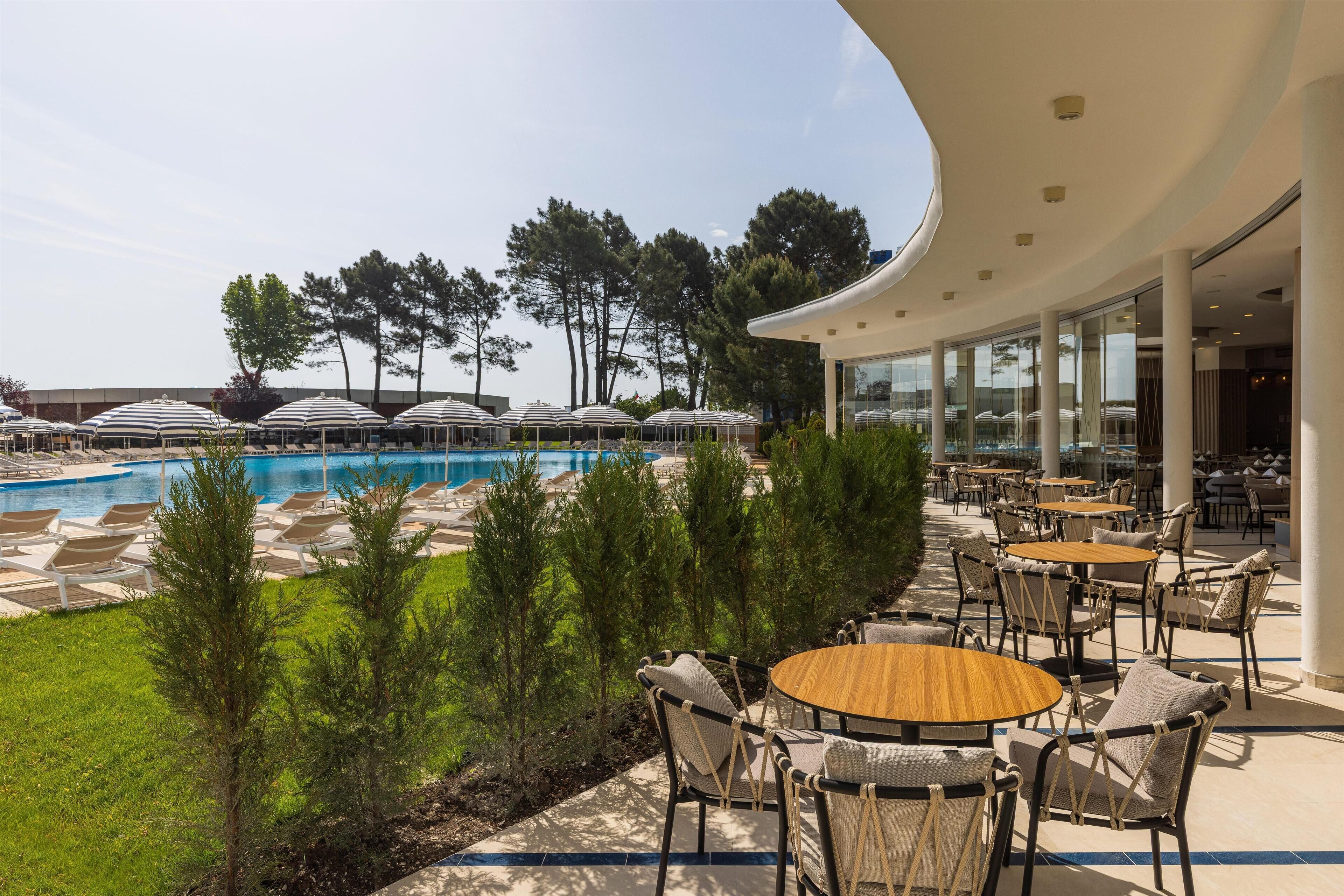 Un área junto a la piscina con sillones de descanso y sombrillas, una piscina y mobiliario exterior.