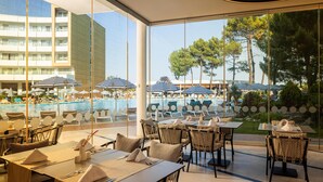 A restaurant with outdoor seating overlooking a pool and a view of a building with multiple floors. - AluaSoul Sunny Beach - All Inclusive – Adults Only  (Sunny Beach)
