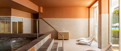 A modern spa area with a hot tub, wooden cabinets, and lounge chairs.