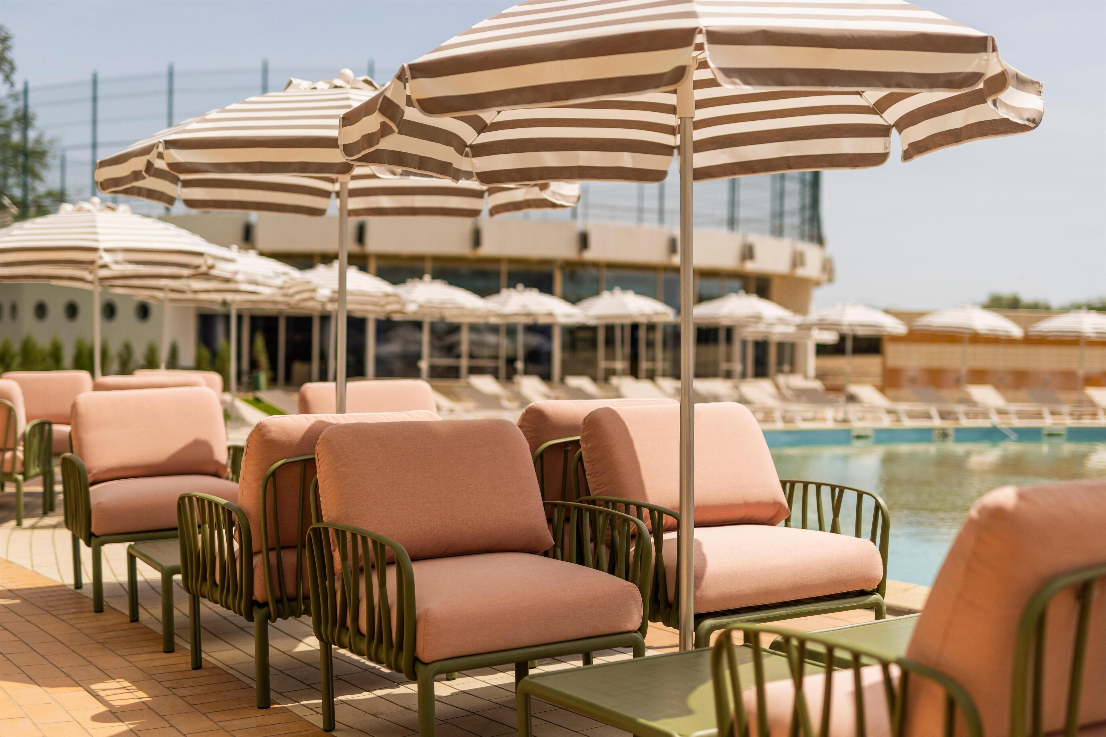 A poolside area with lounge chairs and striped umbrellas.