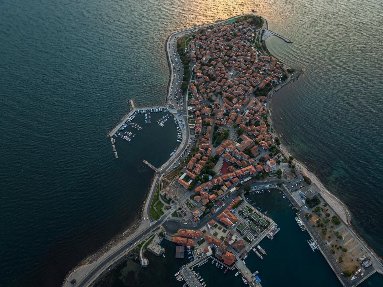 An aerial view of a coastal town with a marina, residential buildings, and a prominent bridge.