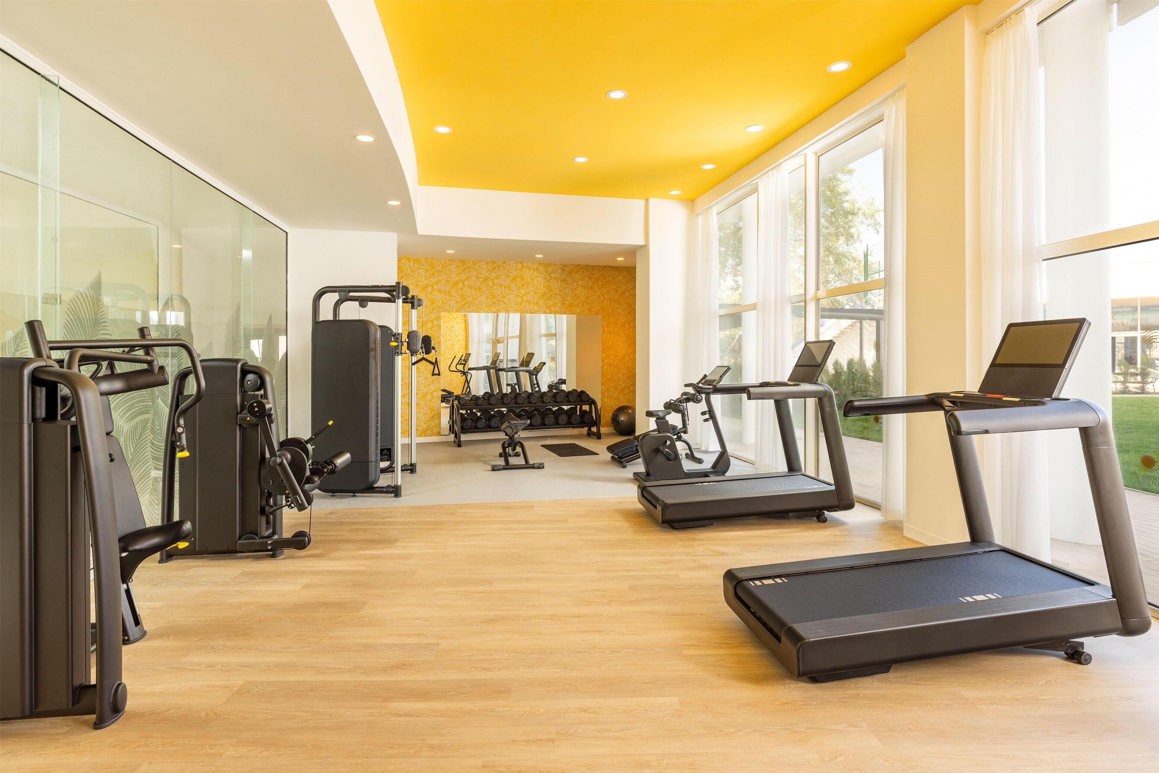 Una palestra moderna dotata di attrezzature cardio, macchinari per pesi e tapis roulant.