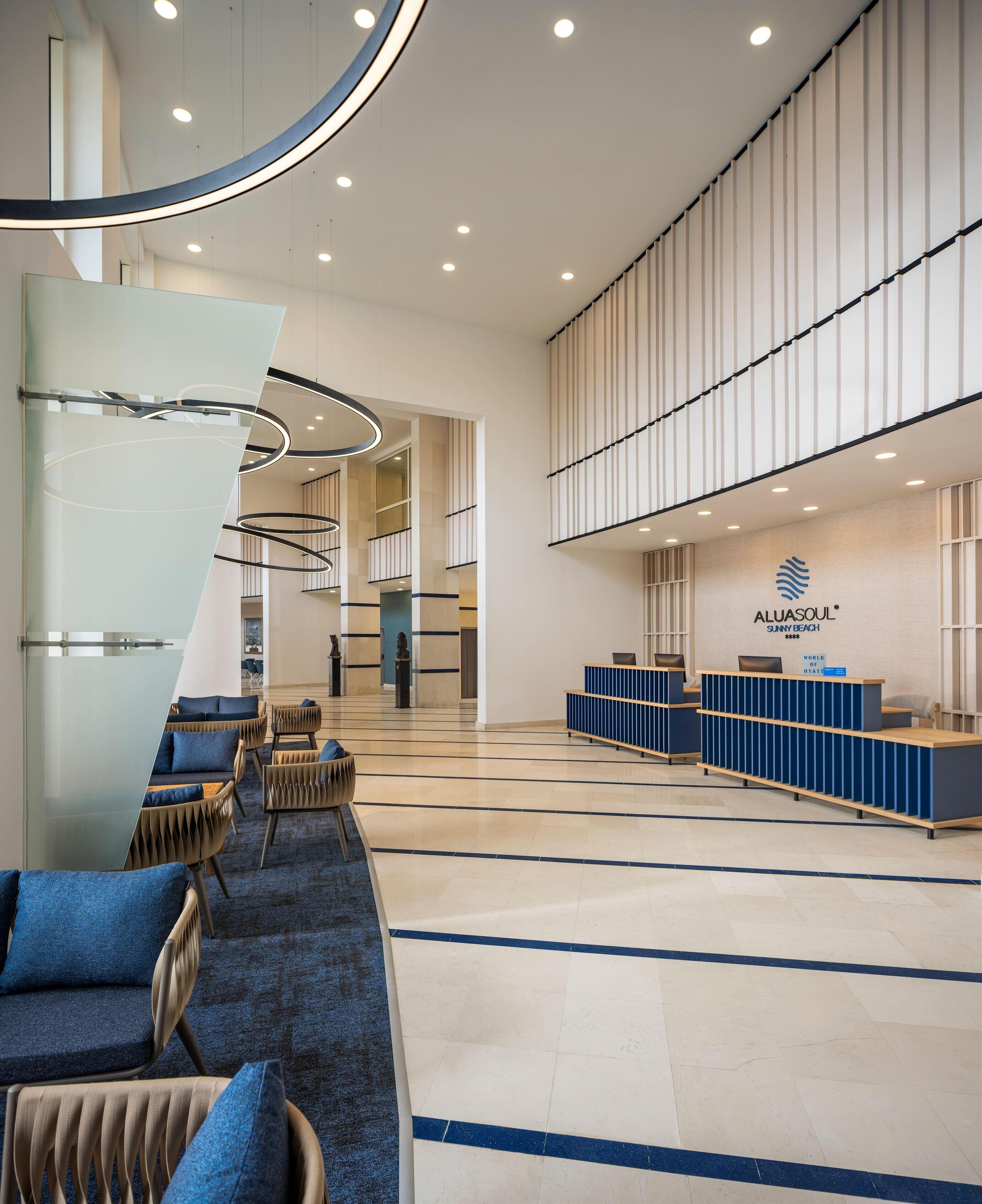 A spacious lobby with a reception desk, seating area, and a staircase leading to upper floors.