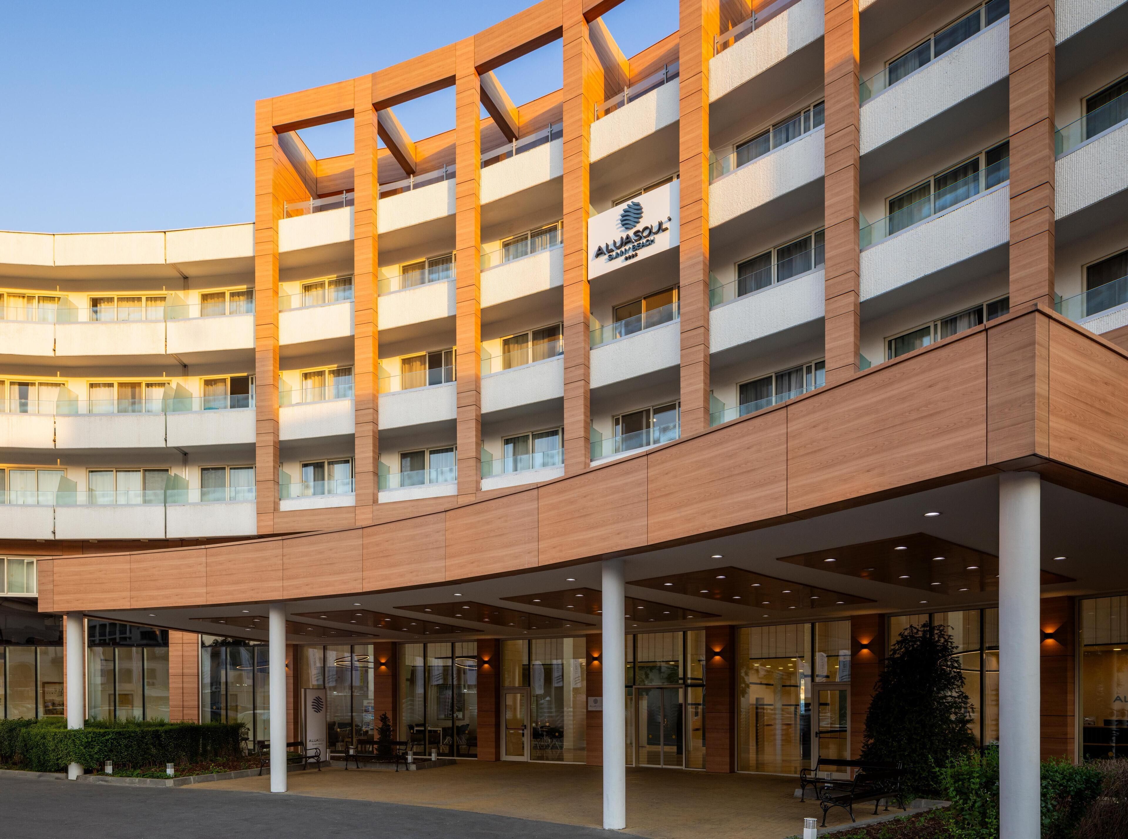 A multi-story hotel with a modern design, featuring a prominent entrance with glass doors and a covered area.