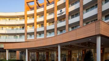 A multi-story hotel with a modern design, featuring a prominent entrance with glass doors and a covered area.