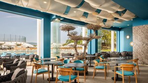 A modern restaurant with blue and white decor, round tables, and comfortable seating. - AluaSoul Sunny Beach - All Inclusive – Adults Only  (Sunny Beach)