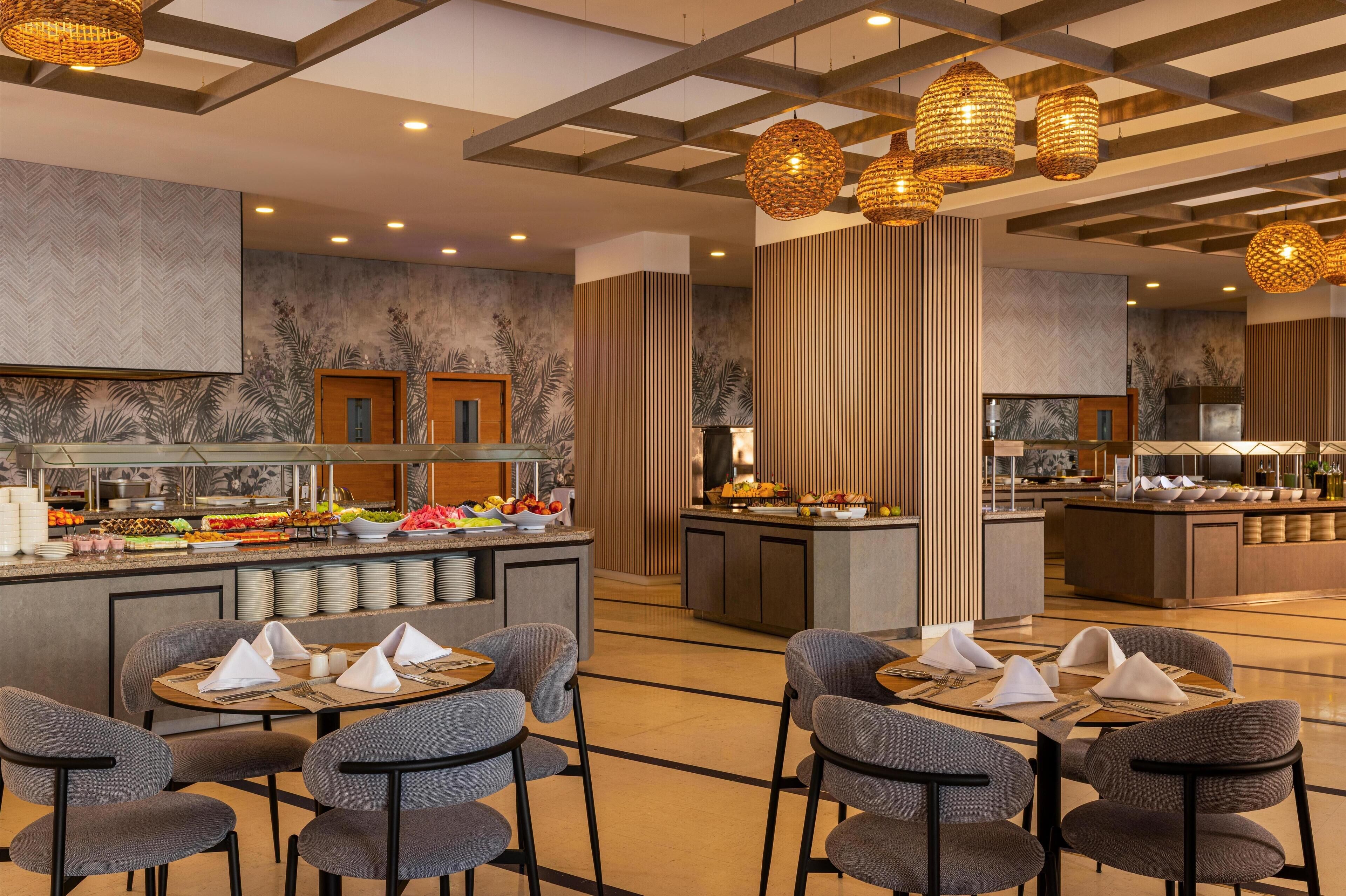 Een moderne hotellobby met een buffetgedeelte, zitruimtes en decoratieve verlichting.