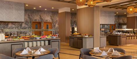A modern hotel lobby with a buffet area, seating arrangements, and decorative lighting.