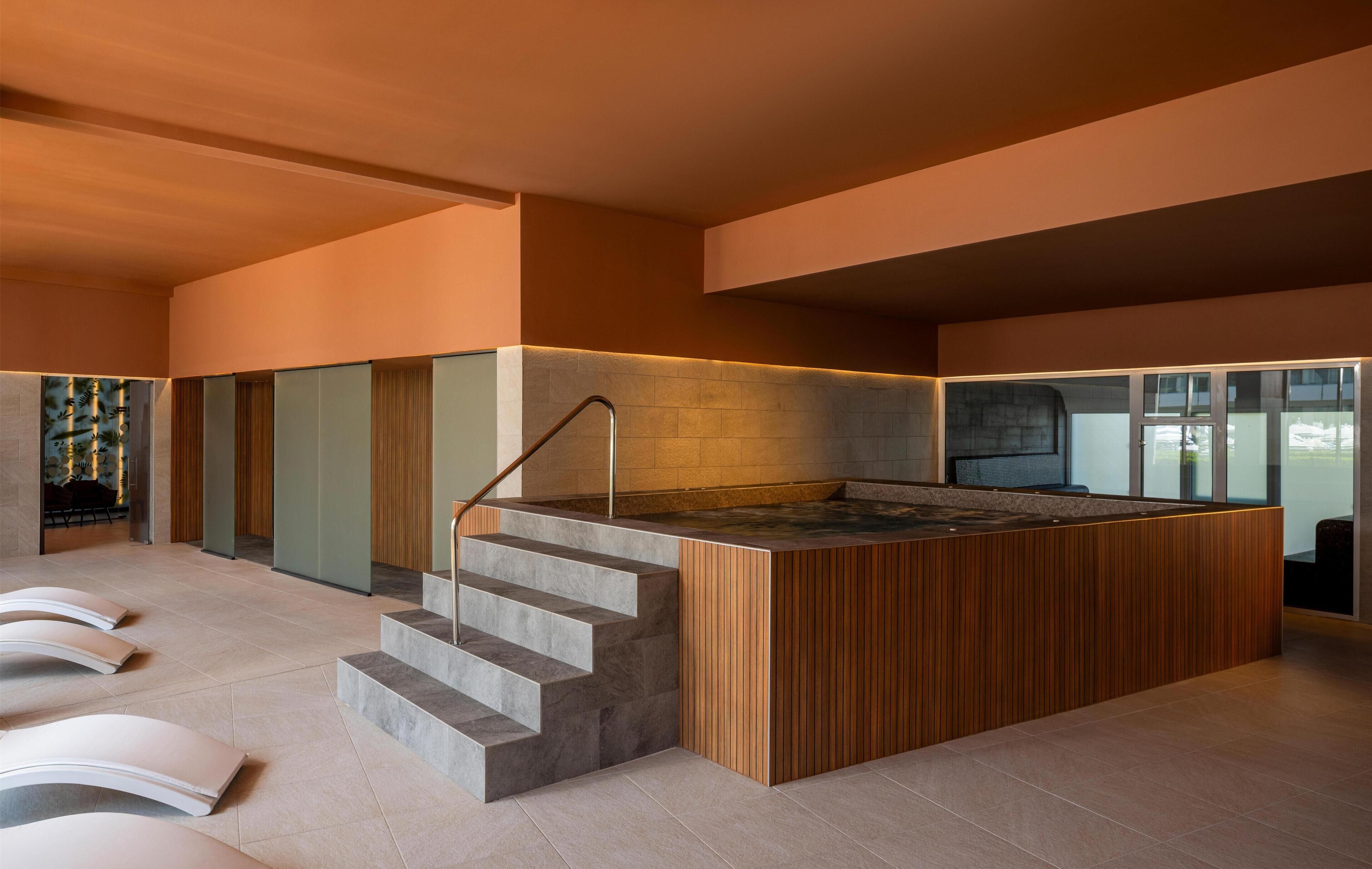 Um interior moderno com uma ilha central, uma escadaria e um espaço de estar.